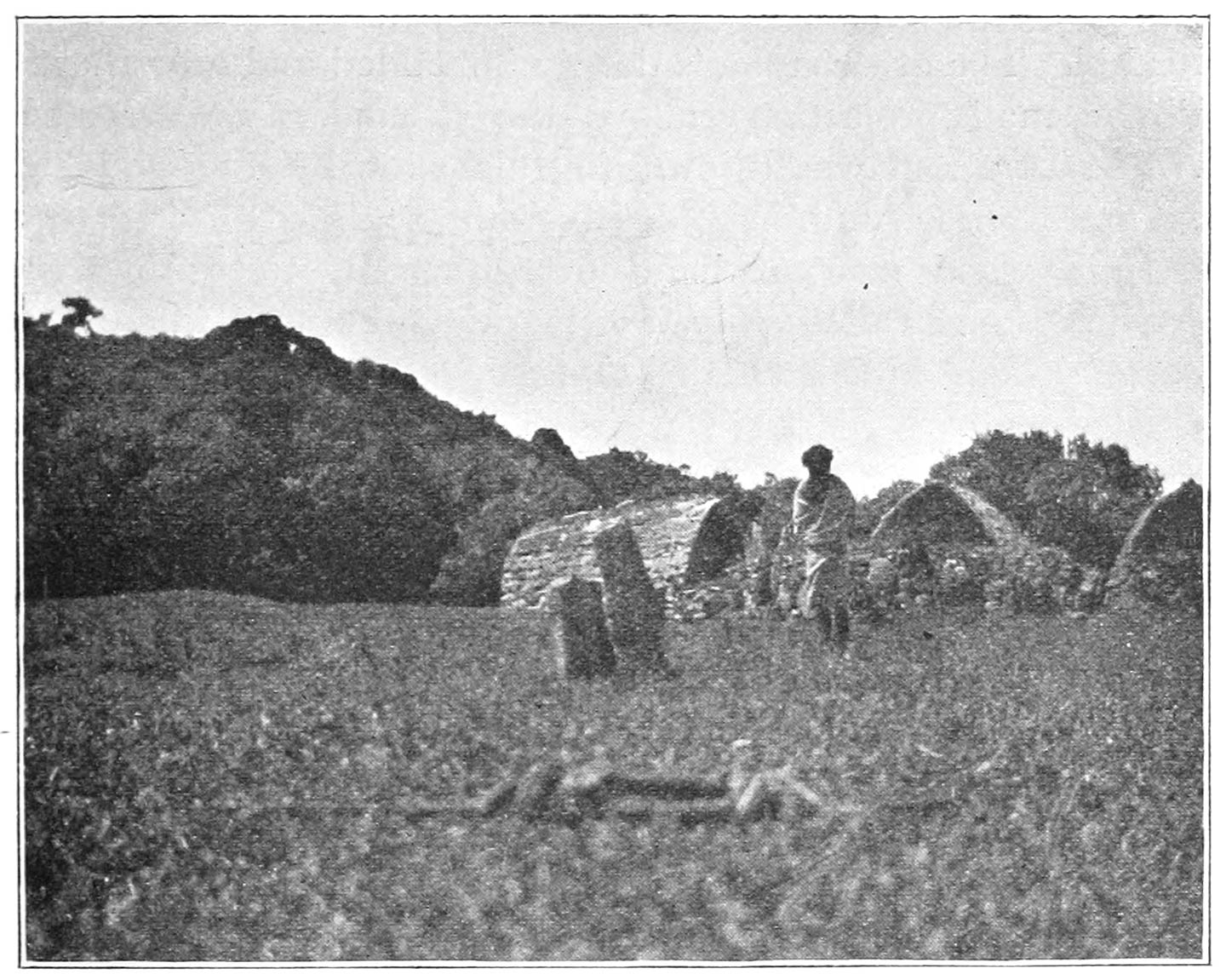 FIG. 72.—THE VILLAGE OF UMGAS, SHOWING THE ‘NADRKKARS’ IN THE CENTRE. BEHIND THE STONES IS THE ‘POH’ OF THIS VILLAGE, AND ON ITS RIGHT ARE THE DWELLING-HUTS.